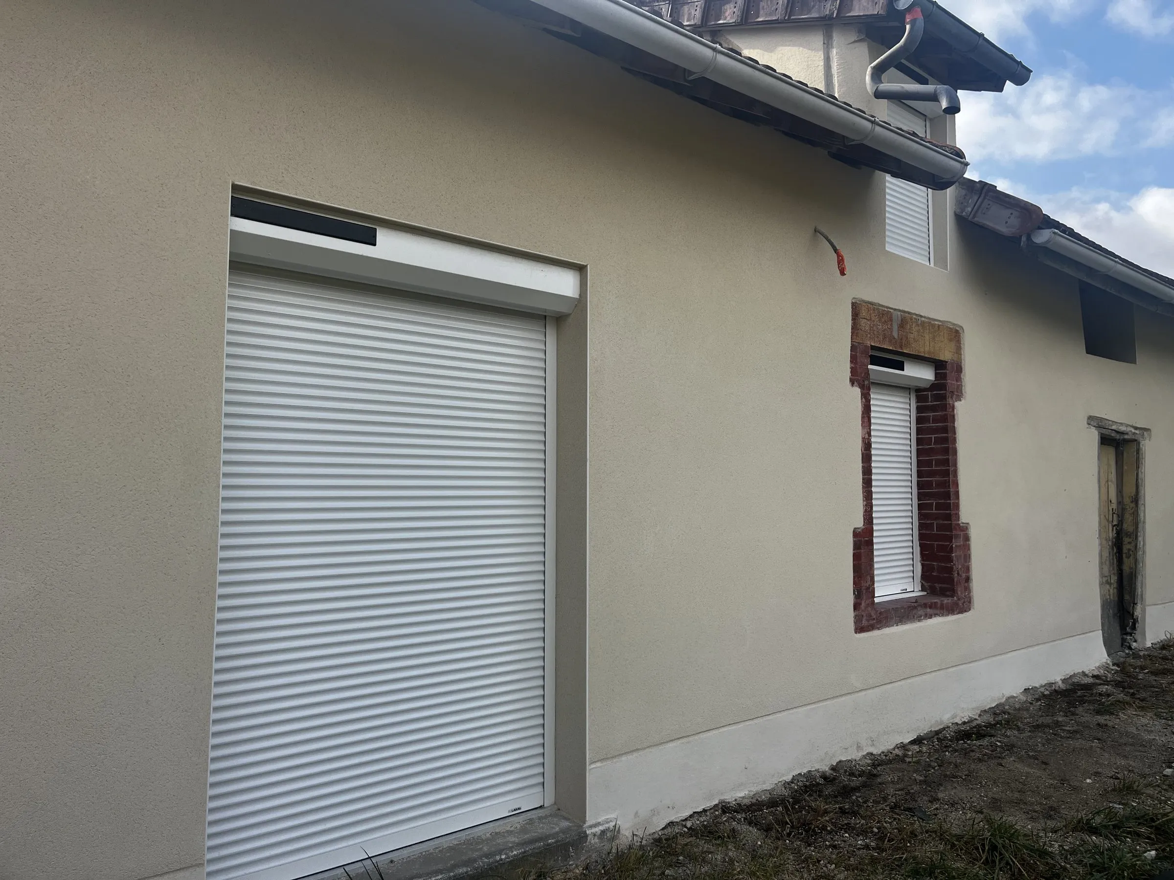 Façade enduite et ses encadrements de fenêtre en brique
