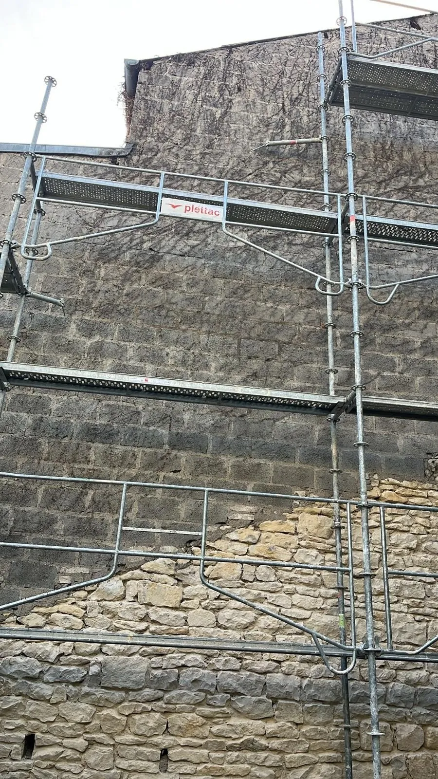 Le pignon avant travaux : parpaing nu et vieille vigne en partie haute, pierre en partie basse, échafaudage monté
