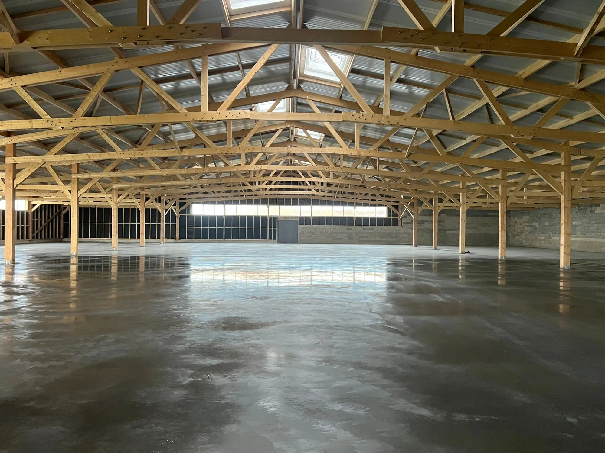 Zone de vente Emmaüs à Magny-Cours : dallage béton finition quartz et murs réalisés par Art et Construction, sous la charpente bois