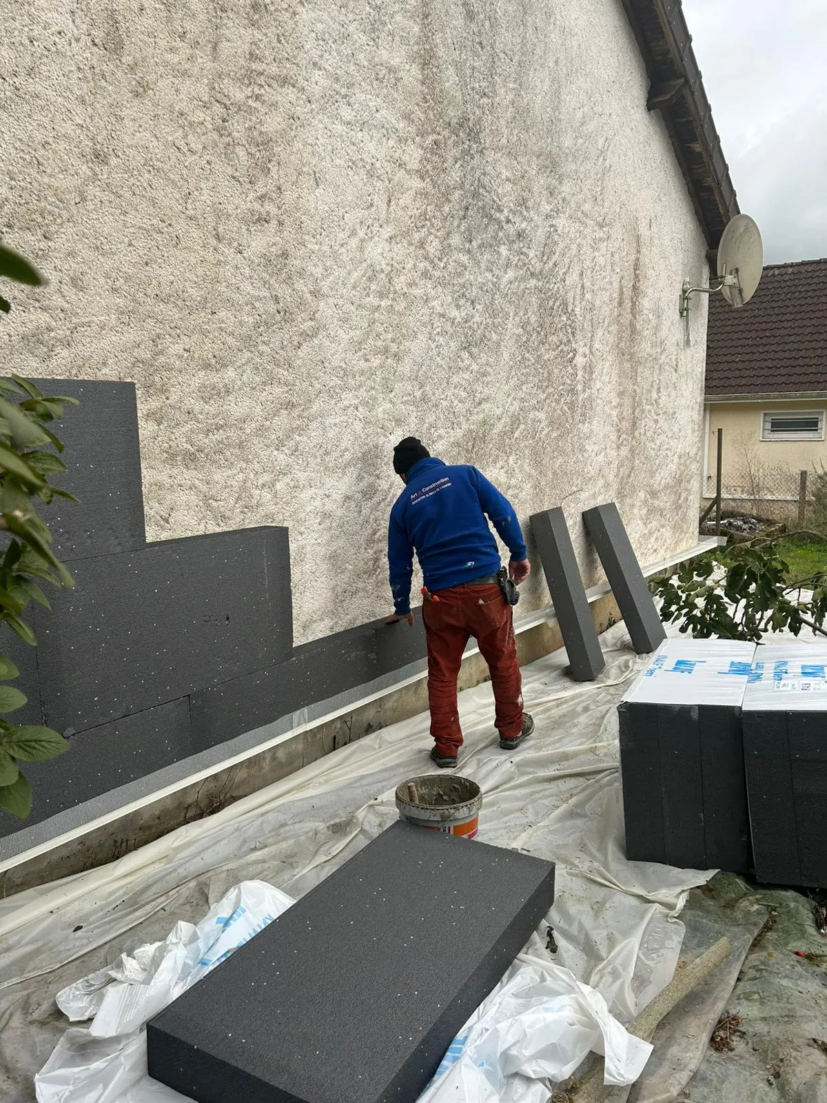 Un compagnon d’Art et Construction pose l’isolant sur une façade