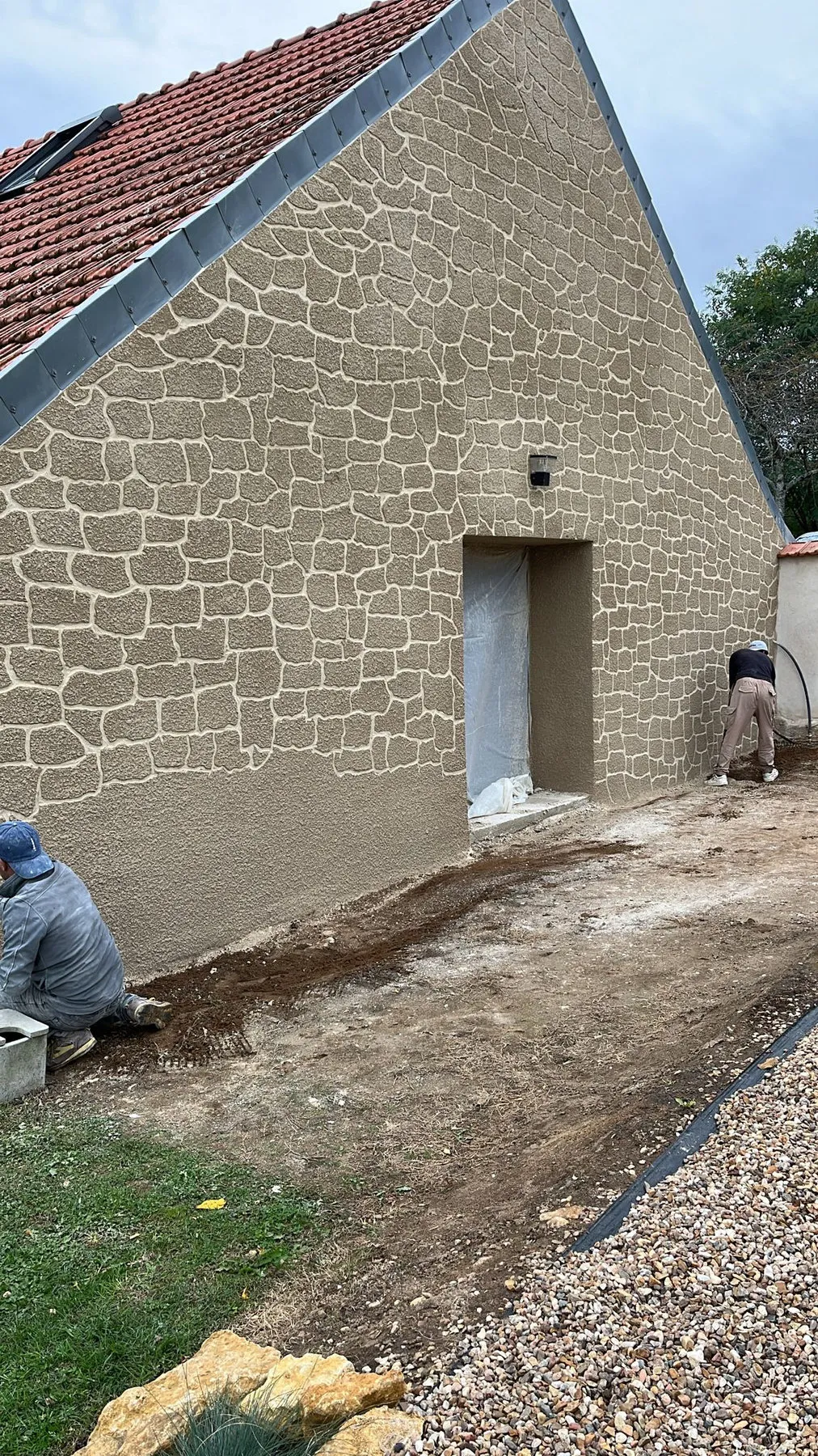 Travail de l’enduit au pied du mur