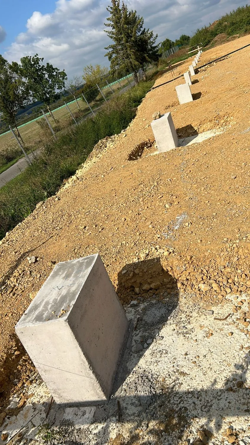 File de fûts béton alignés le long du futur bâtiment